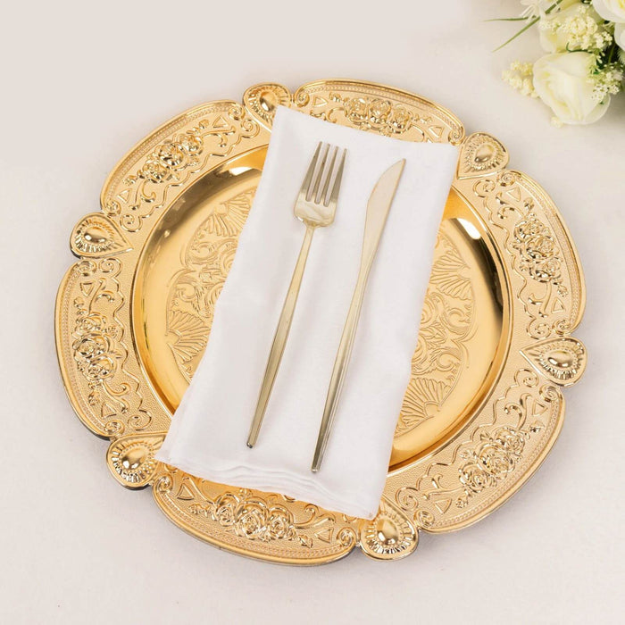 Gold ornate charger plate with silver cutlery and white napkin.