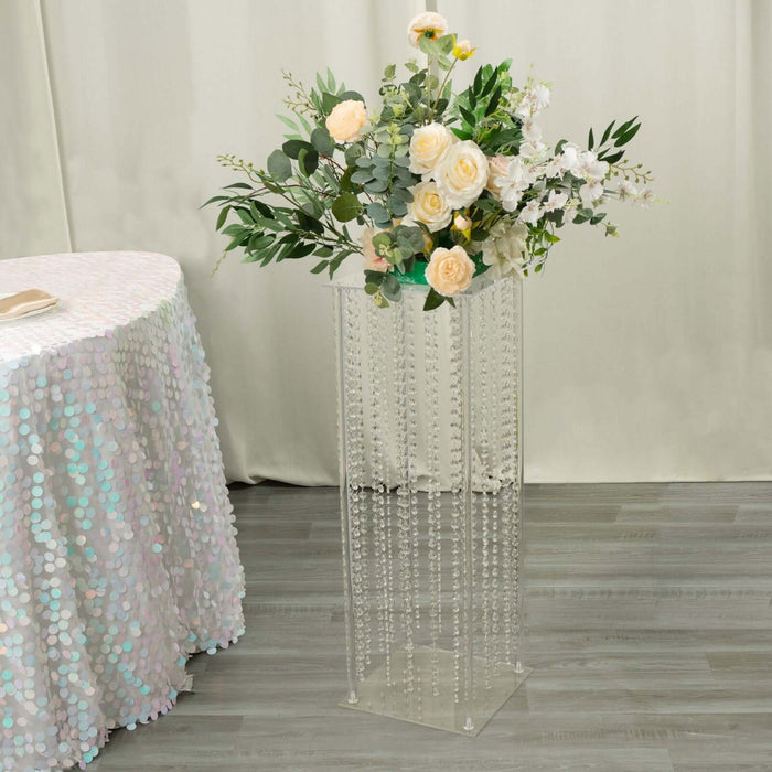 Clear acrylic flower stand with floral arrangement and decorative beads.