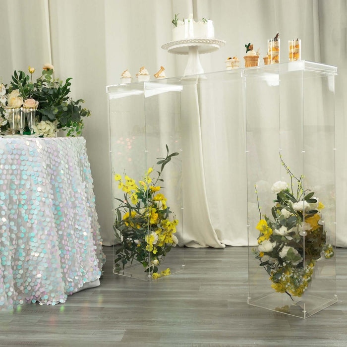 Acrylic display tables with floral arrangements at a stylish event.