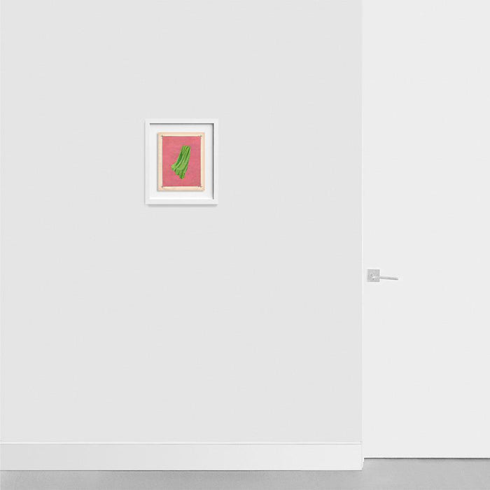 Framed print Color Play 132 with a green fabric element on pink hanging on a light gray wall next to a white door