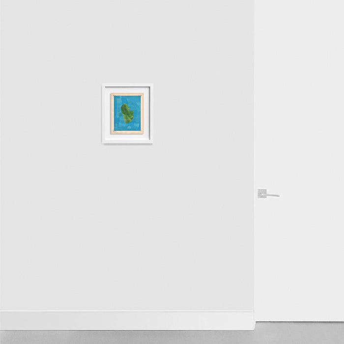 Small framed print on a light grey wall A green folded fabric shape on a blue background in a white frame