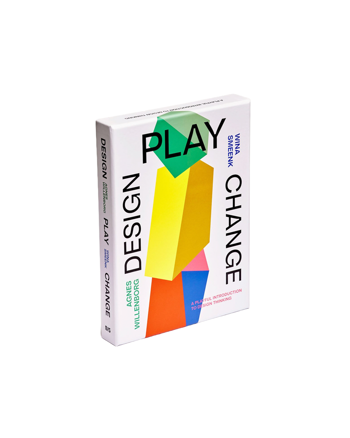 The book 'Design Play Change' by Yvon D'Amour and Vincent Willendorf, featuring a white cover with bold black typography and a colorful geometric illustration of stacked blocks in green, yellow, orange, and pink.