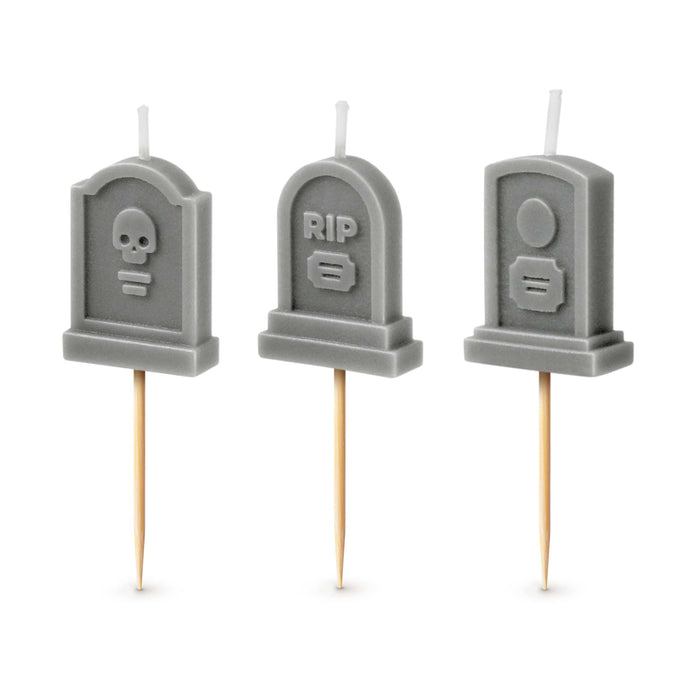 Three gray tombstone-shaped candles with various designs on a white background.