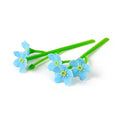 A bookmark with three blue flowers with green stems on a white background