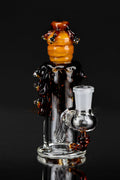 Close-up front view of the Mini Rig - Beehive Nano showing a glossy amber beehive cap and textured dark drips on clear glass against a black background
