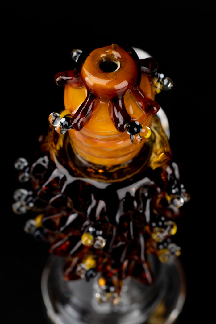 Close-up top-down view of the amber glass Mini Rig - Beehive Nano with bead-like protrusions against a black background