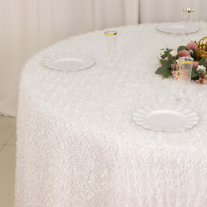 Elegant white textured tablecloth on round table with floral centerpiece.