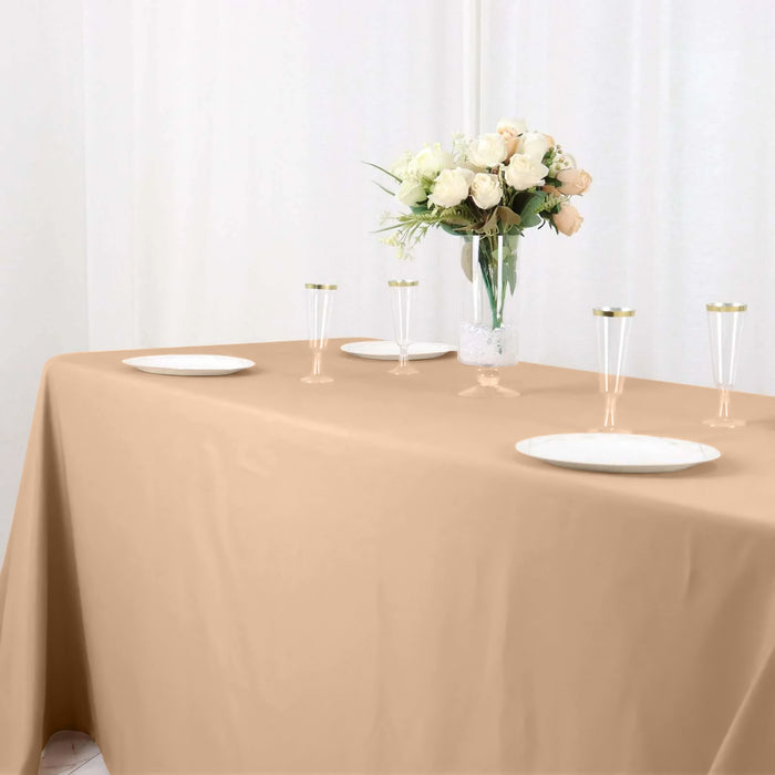 Elegant beige tablecloth set with plates and a floral centerpiece.