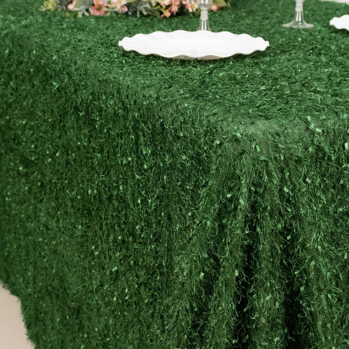 Green textured tablecloth draping over a table set with white plates.