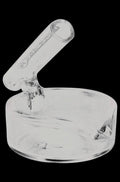 A close-up, angled view of the Pulsar Concentrate Dish with Dabber Holder, showcasing its clear glass construction and integrated tool rest.