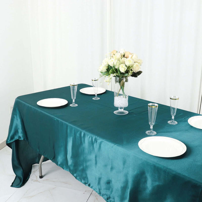 Elegant teal tablecloth set for a dining table with plates and floral centerpiece.