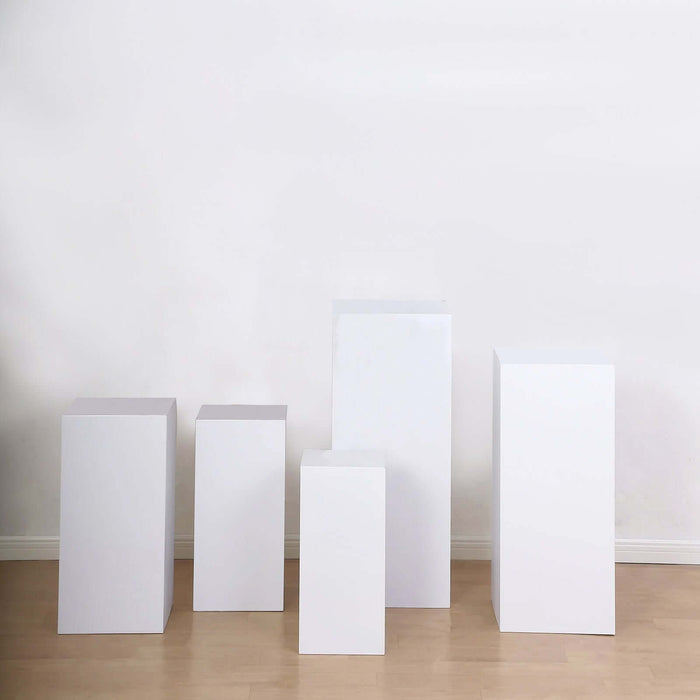 White display pedestals in various heights on a plain backdrop