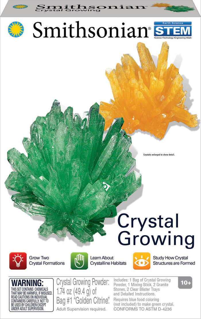 The Smithsonian Crystal Growing Value Set box displays large green and yellow crystal models, educational icons, and info on growing two crystals. This Smithsonian STEM kit offers a geology experiment for ages 10+. Warning label appears at the bottom.