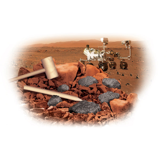 A Mars rover explores a rocky, reddish Martian landscape. In the foreground, a wooden hammer and chisel from the Smithsonian Mars Dig by Smithsonian rest on orange rocks and dark stones. Rolling hills appear in the distance under a hazy sky.