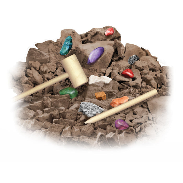A mound of brown clay-like material with colorful gemstones inside, topped with a wooden mallet and chisel, suggests the Smithsonian Rock and Gem Dig excavation STEM kit by Smithsonian.