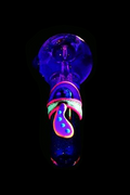 Glow-in-the-dark glass pipe shaped like a mushroom against a black background.
