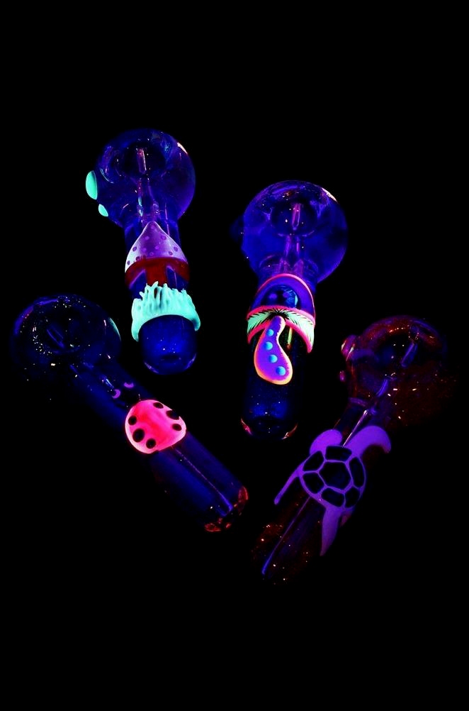 Neon-lit glass pipes with colorful, whimsical designs against a black background.
